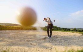 man sweeping at sand on the golf course whilst trying a bunker shot!